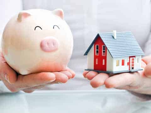 Hands holding a piggy bank and a house model