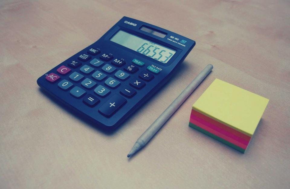 Calculatrice bleue, stylo et notes adhésives sur un bureau