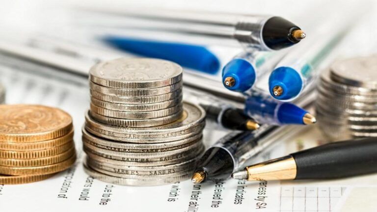 Piles de pièces de monnaie et stylos posés sur un relevé chiffré