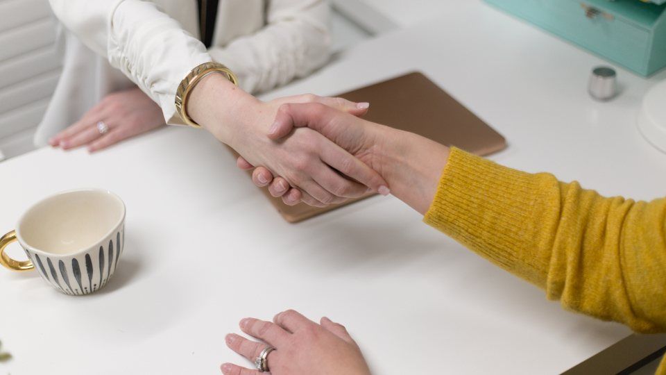 Poignée de main entre un vendeur et un acquéreur autour d'un bureau